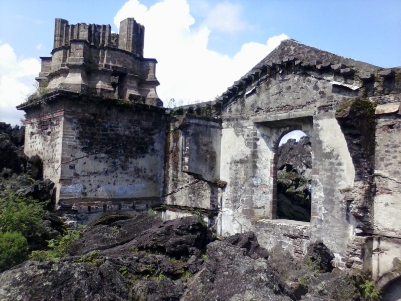 A ruined church bell tower poking up from the ground in Mexico.