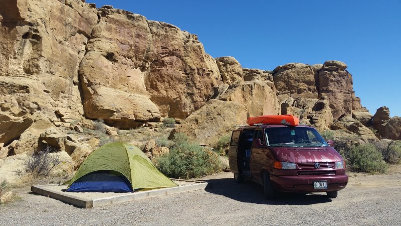 A burgundy Volkswagen van and a green and blue tent at a Chaco Canyon camping site.