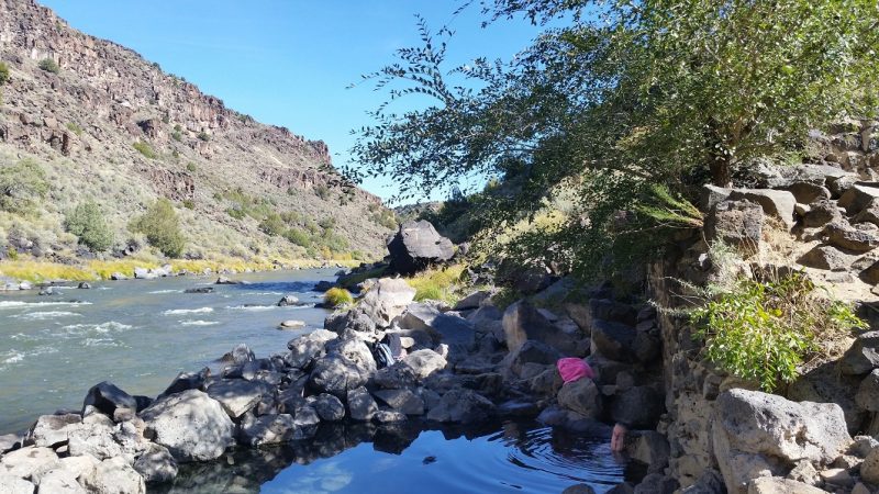 A woman in a hot spring pool along the Rio Grande River in an area known for outstanding New Mexico scenery near Taos.