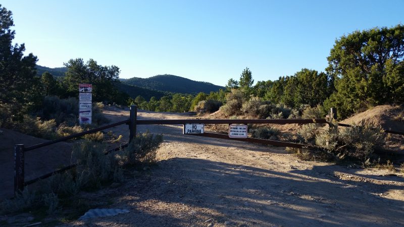 A closed gate with several signs on it going across the old road to Ponce de Leon hot springs near Taos, New Mexico.