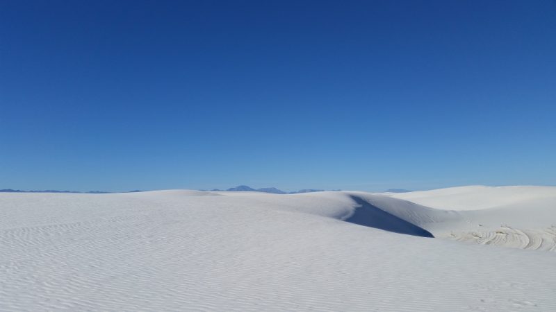 A white sand dune against a clear blue sky. 