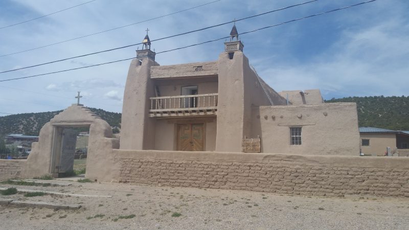 An adobe church surrounded by an adobe wall on the High Road to Taos Scenic Byway in New Mexico.