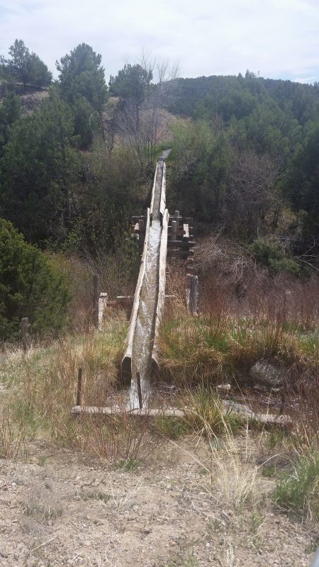 A wooden flume channeling water on the side of New Mexico Route 76.