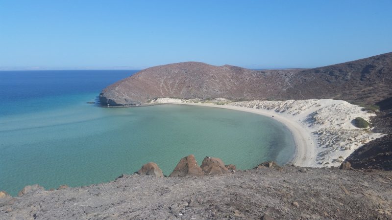 White sand beach with mountains in the background.