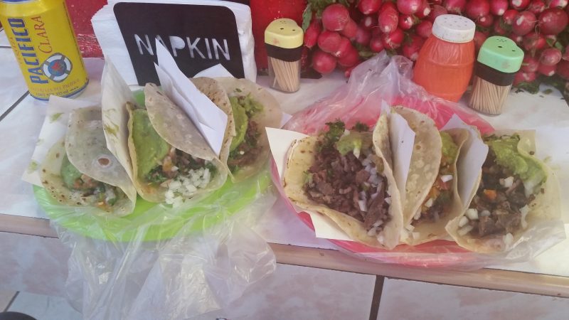 Two plates of beef tacos with a beer and radishes from a taco stand in Baja California.