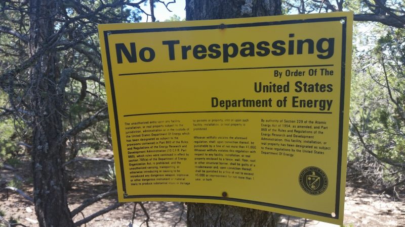 A yellow no trespassing sign nailed to a tree.