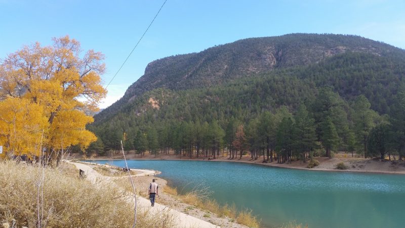 A lake with milky blue water and a green mountain in the background on The Enchanted Circle Scenic Byway, one of the popular scenic drives in New Mexico near Taos.