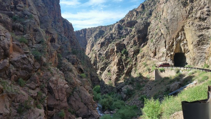 View of narrow Guadalupe Box Canyon with a burgundy van parked at the entrance of Gilman Tunnel north of Albuquerque.