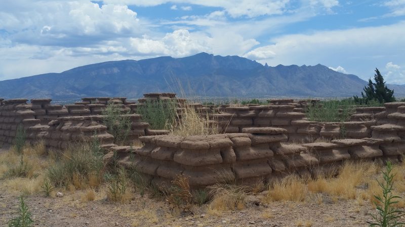 Adobe ruins with the Sandia Mountain range in the background.
