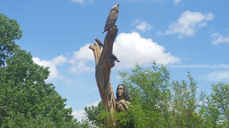 A tree stump carved into a figure of an owl and a woman.