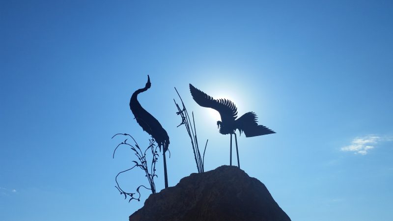 A sculpture of herons silhouetted against a blue sky along the free Paseo del Bosque Trail in Albuquerque.