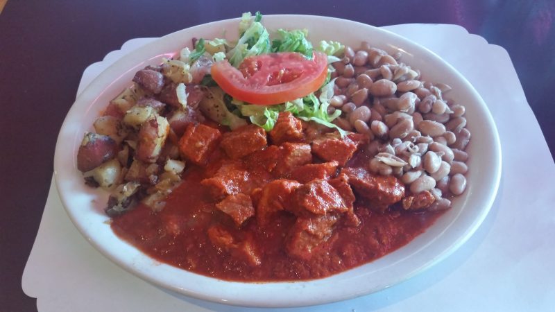 A plate of carne adovada with beans, potatoes and salad from a cheap place to eat in Albuquerque.