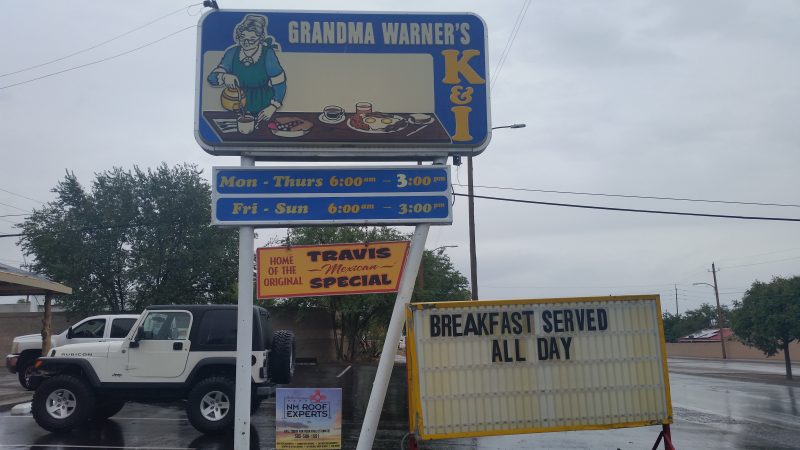 A sign for Grandma Warner's K & I Diner with two white vehicles behind it in Albuquerque, New Mexico.