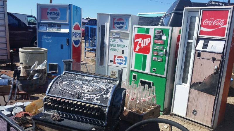 Vintage 7up and Pepsi vending machines and an old cash register at a flea market in Gallup, New Mexico.
