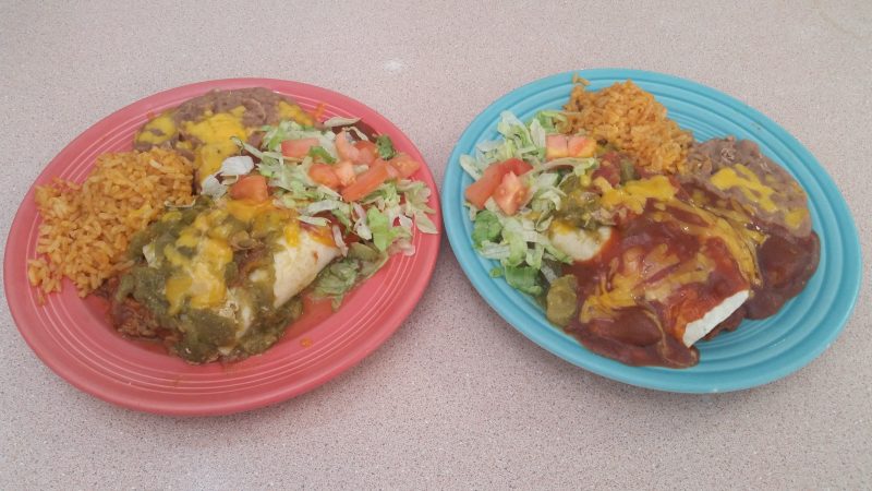 Two colorful plates of burritos with rice and beans on the side.