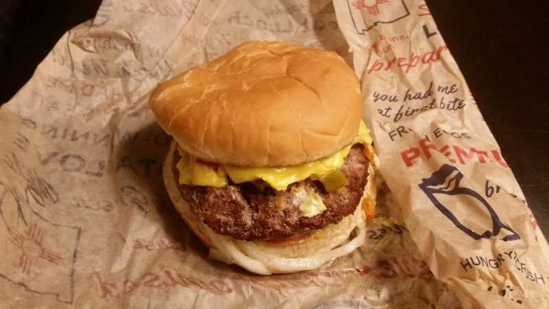 A green chile cheeseburger from Blake's Lotaburger sitting on it's paper wrapper.