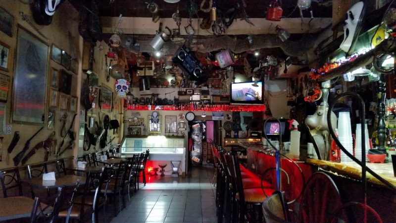 A bar in Chihuahua, Mexico with all sorts of random things hanging off the ceiling and walls.