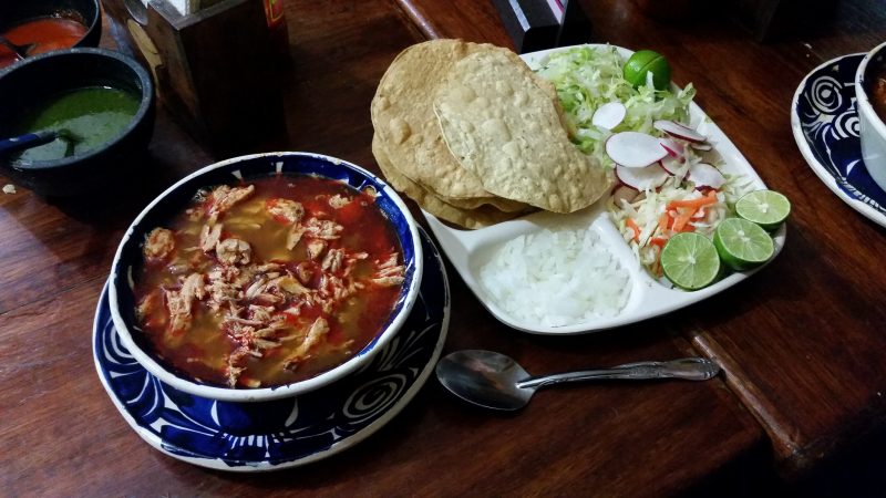 A bowl of pozole stew and a plate of garnishes from one of traditional cenaduria-style restaurants in Mazatlan.