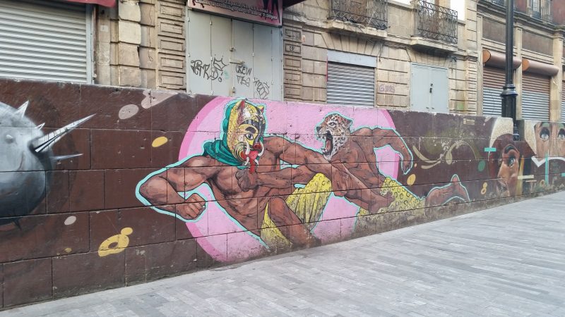A Mexico City street art mural showing two men dressed as jaguars engaging in a fist fight.
