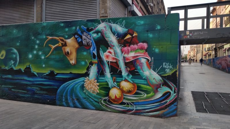 A stylized painting on a wall in Mexico City of a deer wearing a native dance costume.