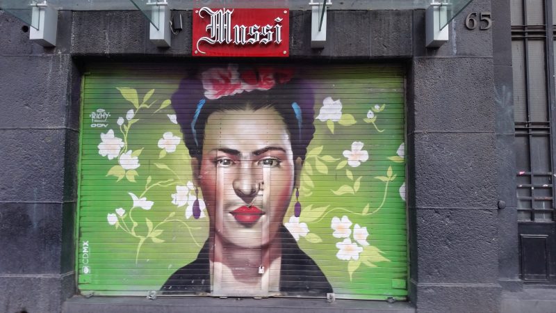 The face of a woman spray painted on the metal shutters of a storefront.