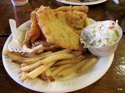 A plate of fish and chips with a side of coleslaw.