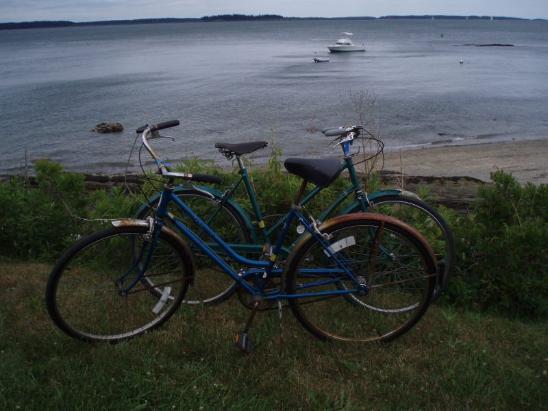 A view from Chebeague Island, Maine of two vintage bicycles with a lobster boat in the background.