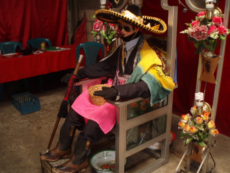 The likeness of San Simon in Zunil, Guatemala, wearing a sombrero and sunglasses, as is typical.