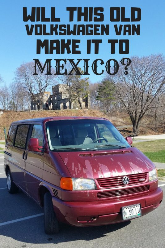 maroon van with stone ruins in the background.