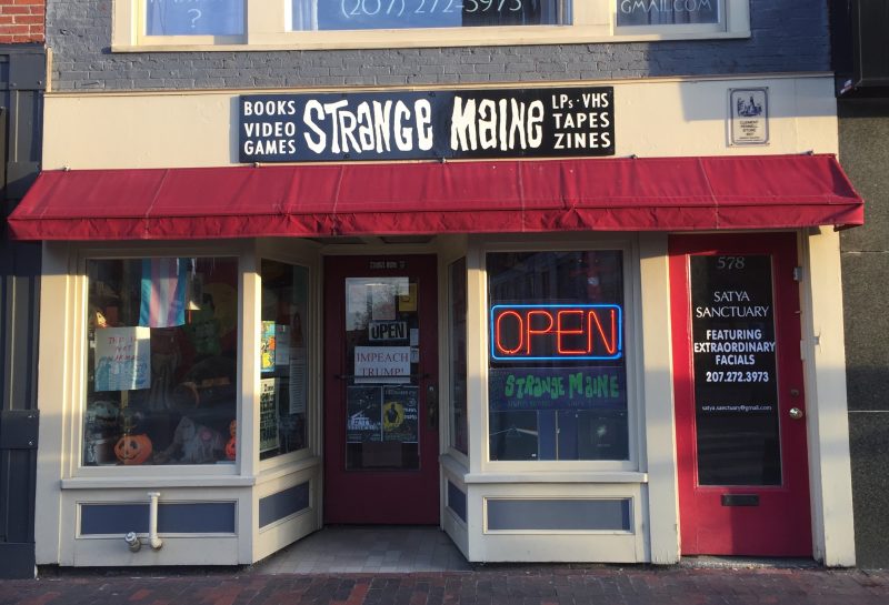 An exterior image of the Strange Maine shop with a small red awning out front.